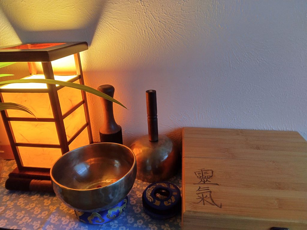 Himalayan singing bowls, strikers and a wooden Reiki box beside a warm shoji lantern