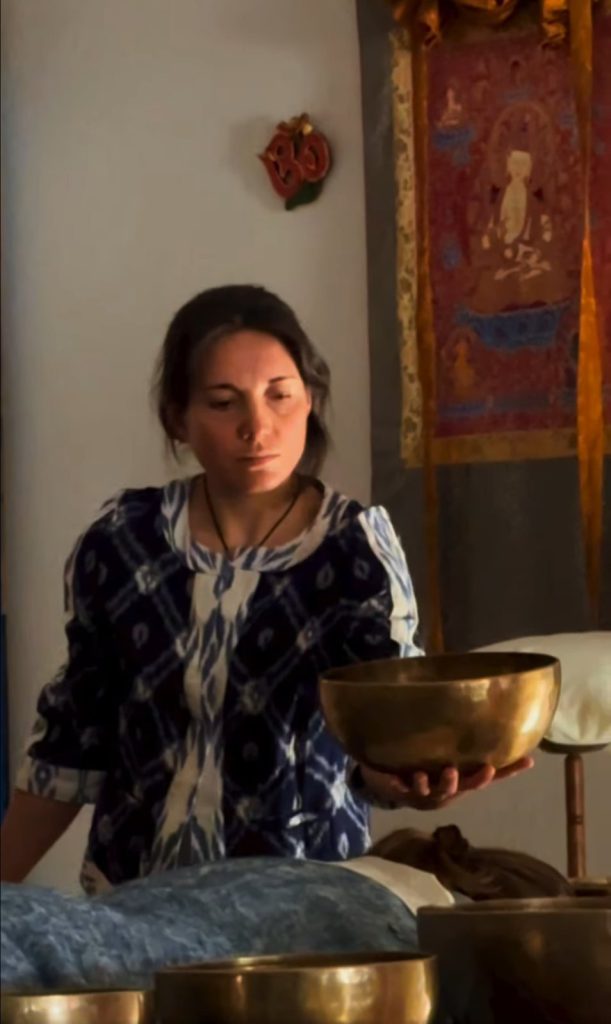 Evolene holding a Himalayan singing bowl above a patient during a sound therapy session