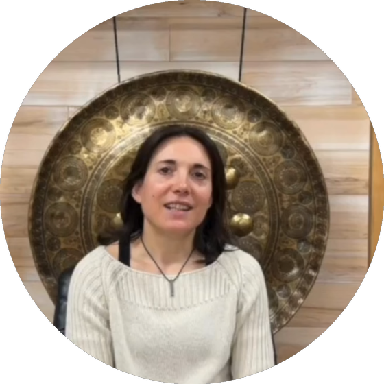 Evolene smiling in front of a large engraved gong